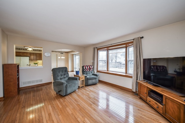 living area featuring a notable chandelier and light hardwood / wood-style flooring