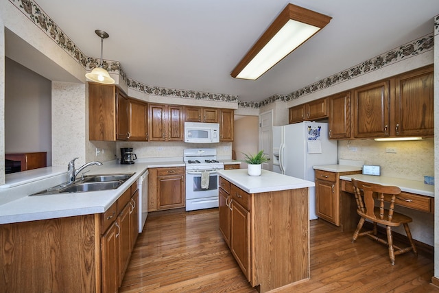 kitchen featuring decorative light fixtures, sink, hardwood / wood-style flooring, kitchen peninsula, and white appliances