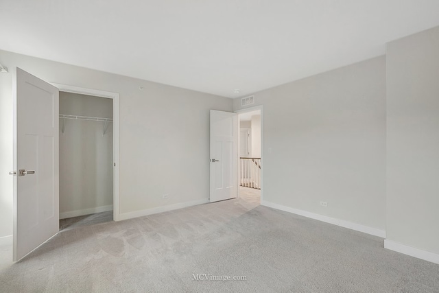 unfurnished bedroom with light carpet and a closet