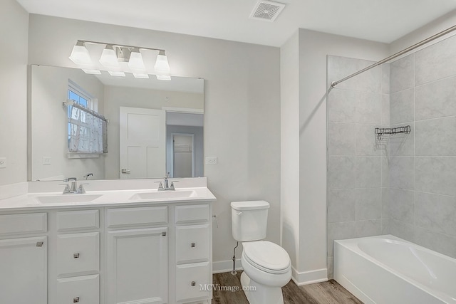 full bathroom with vanity, tiled shower / bath, hardwood / wood-style flooring, and toilet