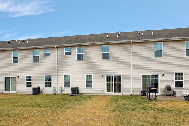 rear view of house featuring a lawn and central air condition unit