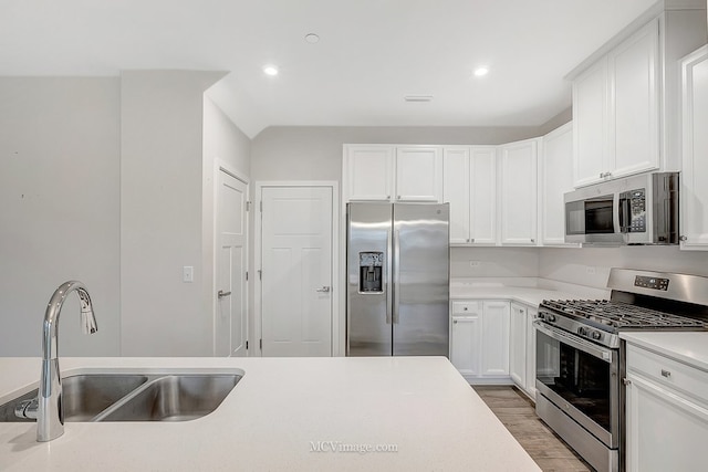 kitchen with sink, light wood-type flooring, white cabinets, and appliances with stainless steel finishes