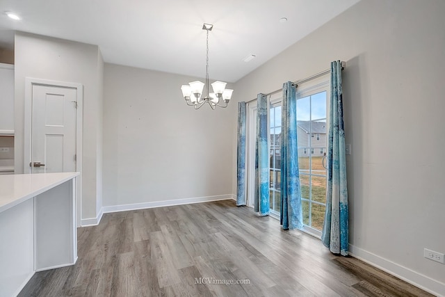 unfurnished dining area with a chandelier and light hardwood / wood-style floors