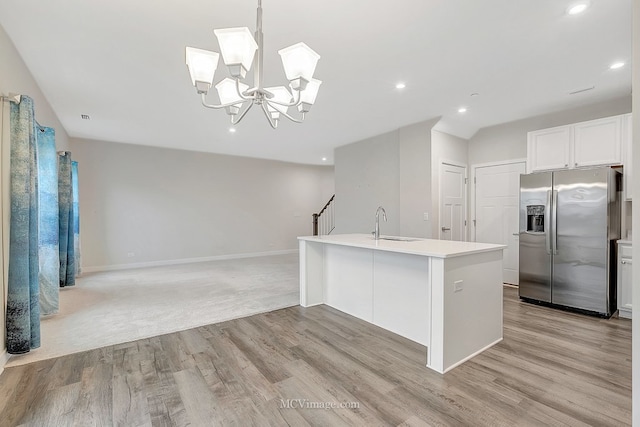 kitchen with white cabinetry, sink, hanging light fixtures, a kitchen island with sink, and stainless steel fridge with ice dispenser