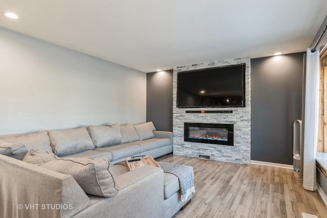 living room with a stone fireplace and light hardwood / wood-style floors