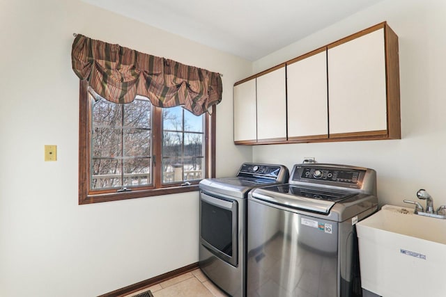 laundry room featuring sink, light tile patterned floors, washing machine and dryer, and cabinets