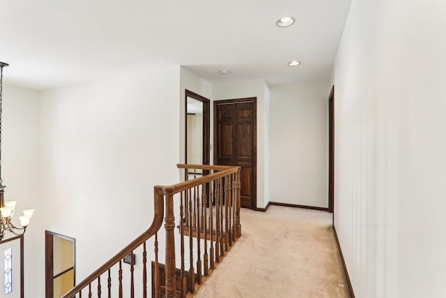 hallway with light carpet and an inviting chandelier