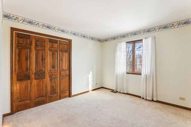 unfurnished bedroom featuring light colored carpet and a closet