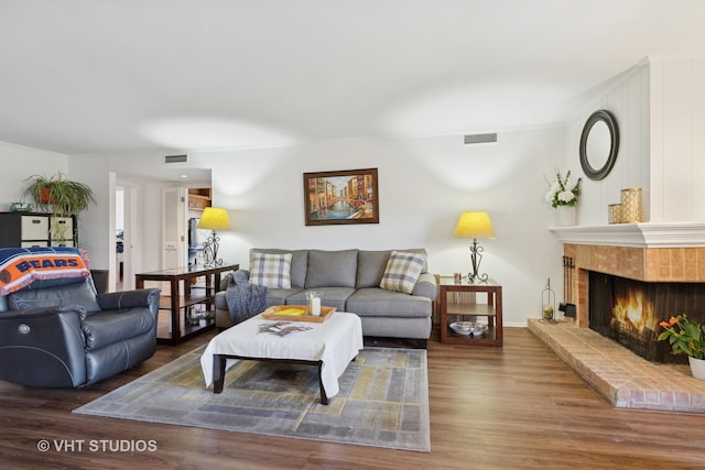 living room featuring a brick fireplace and dark hardwood / wood-style floors