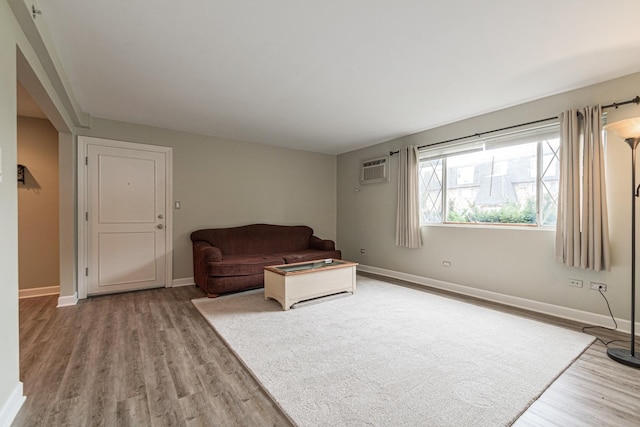 sitting room with a wall mounted air conditioner and hardwood / wood-style flooring