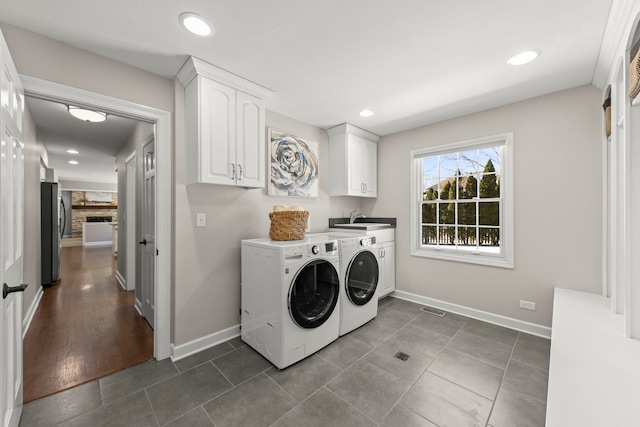 laundry room featuring cabinets, washer and dryer, sink, and dark tile patterned flooring