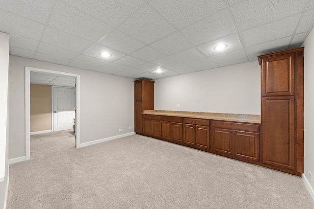 basement featuring a paneled ceiling and light carpet