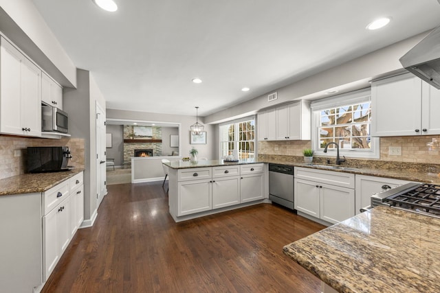 kitchen featuring stainless steel appliances, kitchen peninsula, and white cabinets