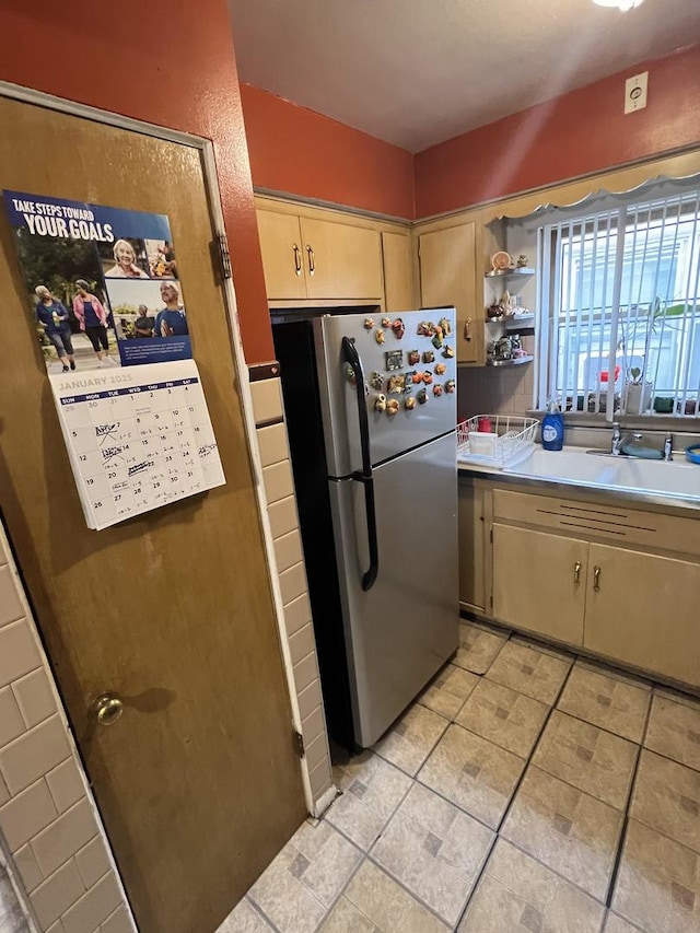 kitchen featuring sink, light tile patterned floors, and stainless steel refrigerator