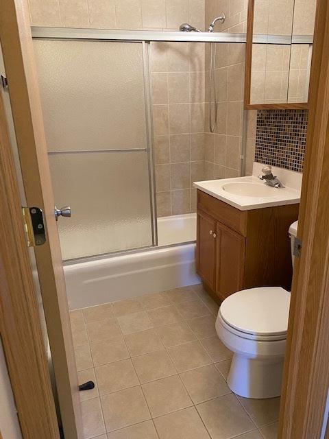 full bathroom featuring toilet, vanity, bath / shower combo with glass door, and tile patterned flooring