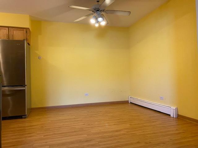 spare room with a baseboard heating unit, ceiling fan, and light hardwood / wood-style flooring