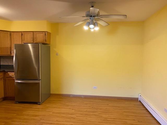 kitchen with ceiling fan, a baseboard heating unit, stainless steel refrigerator, and light wood-type flooring