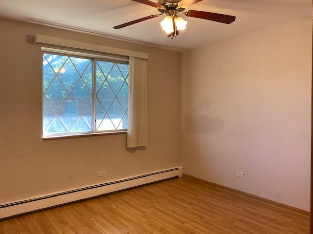 empty room with hardwood / wood-style flooring, a baseboard radiator, and ceiling fan