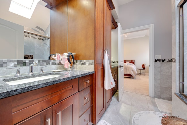 bathroom featuring vanity, tile patterned flooring, a shower with door, and vaulted ceiling with skylight