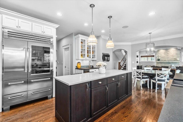 1210 Blackthorn Ln, Deerfield, IL 60015 - kitchen with stainless steel built in fridge, arched walkways, white cabinets, dark wood-type flooring, and glass insert cabinets