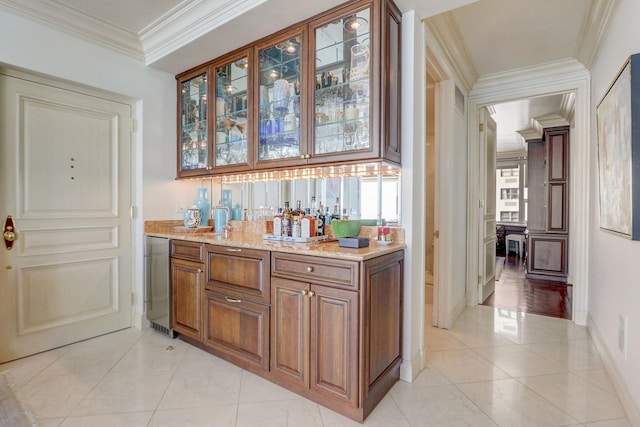 bar featuring light stone counters, ornamental molding, and light tile patterned floors