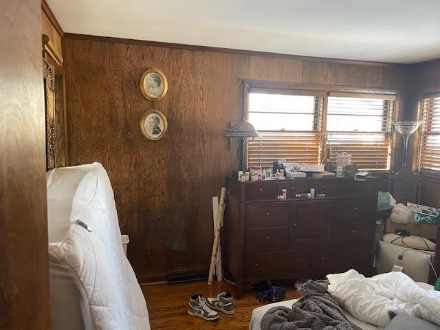 bedroom with dark hardwood / wood-style floors and wood walls