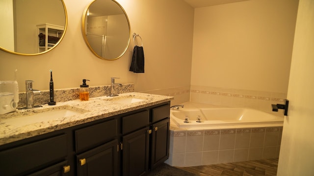 bathroom featuring a relaxing tiled tub and vanity