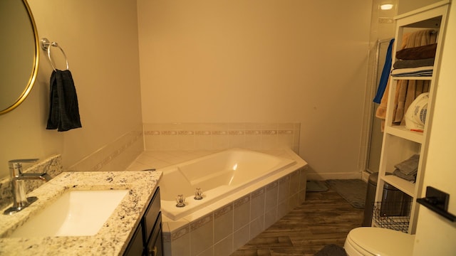 bathroom featuring vanity, toilet, tiled bath, and hardwood / wood-style floors