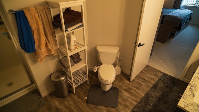 bathroom with an enclosed shower, hardwood / wood-style flooring, and toilet