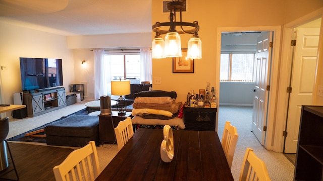 carpeted dining area featuring plenty of natural light and a notable chandelier