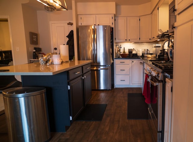 kitchen with appliances with stainless steel finishes, a center island, white cabinets, dark hardwood / wood-style flooring, and decorative backsplash