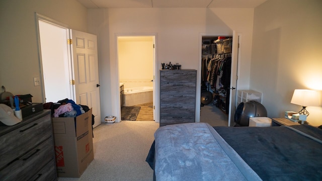 bedroom featuring a walk in closet, ensuite bathroom, carpet flooring, and a closet