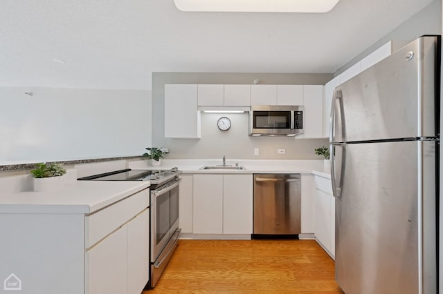 kitchen featuring stainless steel appliances, white cabinetry, sink, and light hardwood / wood-style floors