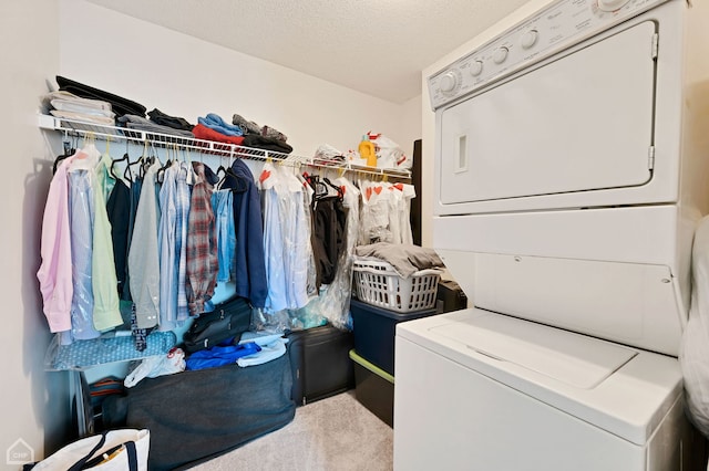 washroom featuring stacked washing maching and dryer, light carpet, and a textured ceiling