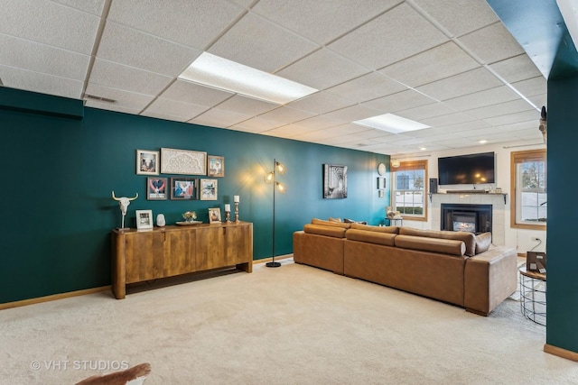 carpeted living room with a paneled ceiling and a tiled fireplace