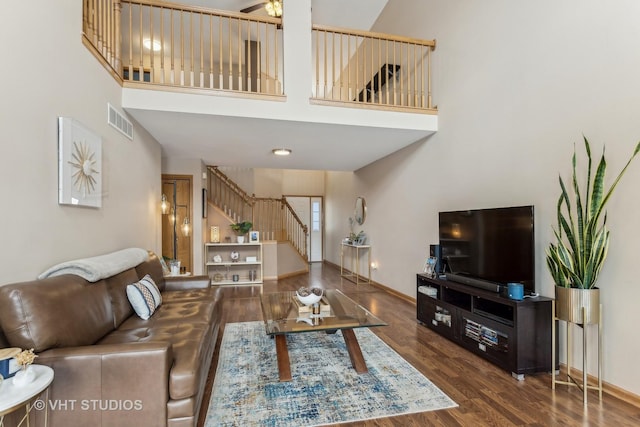 living room featuring dark hardwood / wood-style flooring, a towering ceiling, and ceiling fan