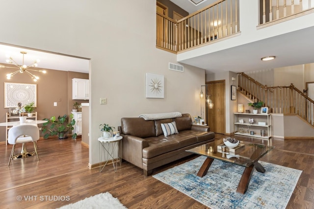 living room featuring a towering ceiling, an inviting chandelier, and dark hardwood / wood-style flooring