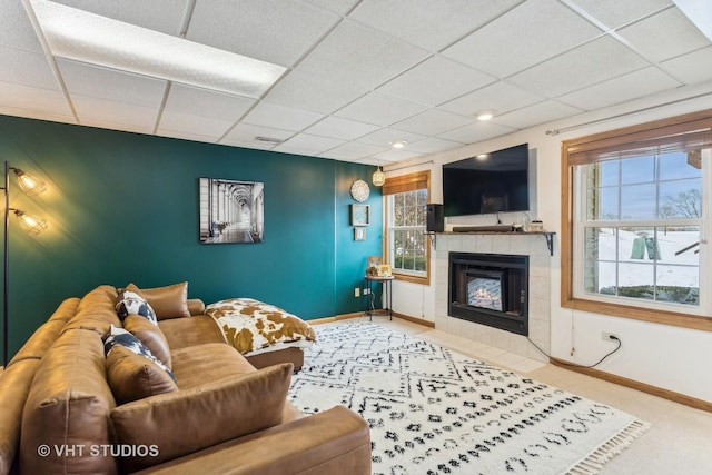 carpeted living room with a tile fireplace and a drop ceiling