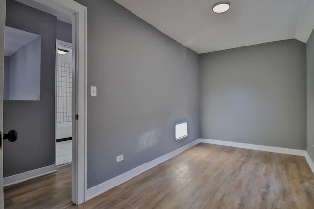 spare room with hardwood / wood-style flooring and lofted ceiling