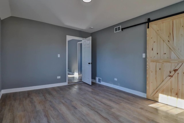 empty room with a barn door and hardwood / wood-style floors