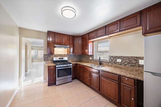 kitchen featuring light tile patterned floors, sink, white fridge, and stainless steel gas range oven