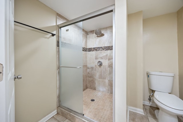 bathroom with tile patterned flooring, toilet, and a shower with shower door