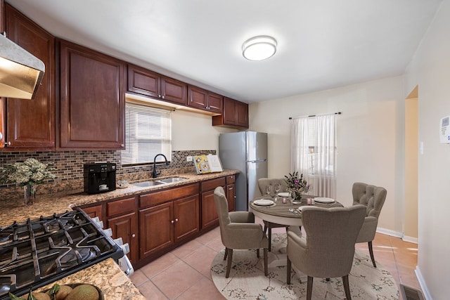 kitchen featuring sink, ventilation hood, light tile patterned floors, appliances with stainless steel finishes, and backsplash