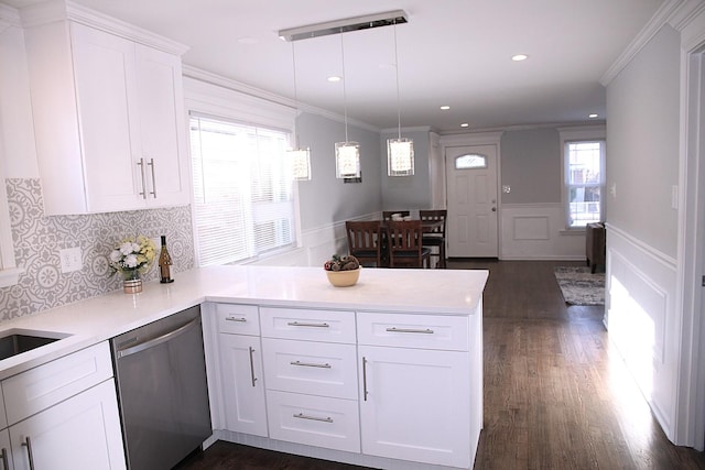 kitchen featuring decorative light fixtures, white cabinetry, ornamental molding, stainless steel dishwasher, and kitchen peninsula