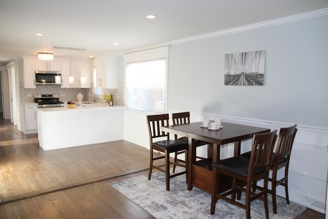 dining space featuring crown molding, sink, and dark wood-type flooring