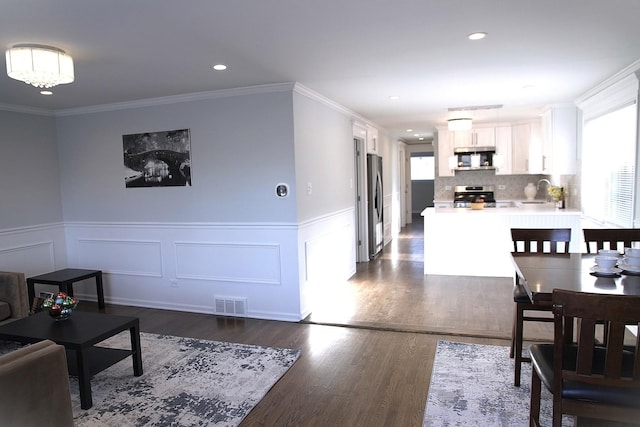 dining room with crown molding, dark hardwood / wood-style flooring, and an inviting chandelier