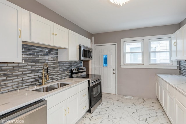 kitchen featuring light stone counters, stainless steel appliances, sink, and white cabinets