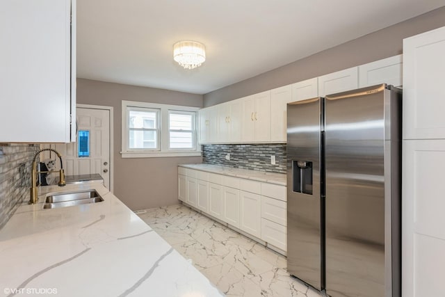 kitchen with sink, tasteful backsplash, white cabinetry, stainless steel fridge with ice dispenser, and light stone countertops