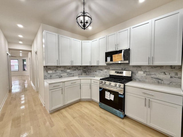 kitchen with pendant lighting, light hardwood / wood-style flooring, white cabinets, and appliances with stainless steel finishes