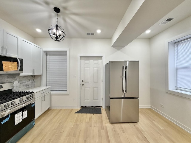 kitchen with white cabinetry, hanging light fixtures, stainless steel appliances, light hardwood / wood-style floors, and decorative backsplash